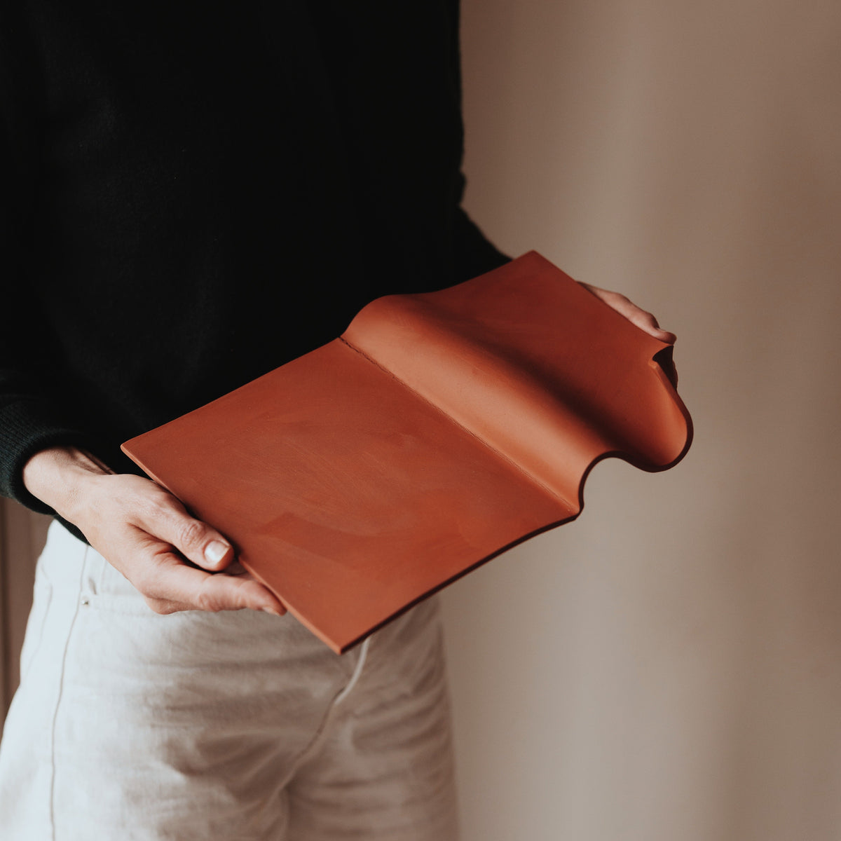 Writings 001 by Studio JOA — Stone Red folded stoneware wall piece held in hand, showing its scale