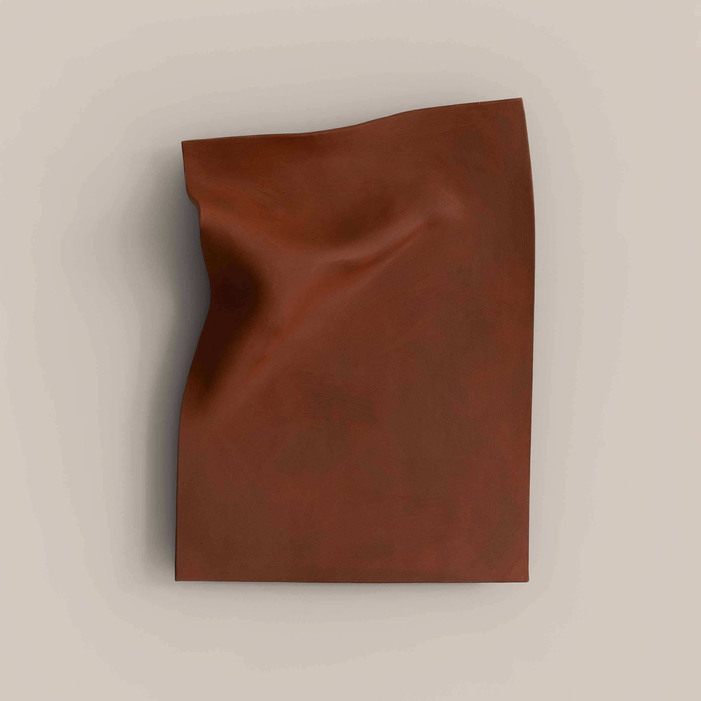 Writings 003 by Studio JOA — Stone Red stoneware wall piece with a pinched vertical fold along one edge, photographed against a plain wall
