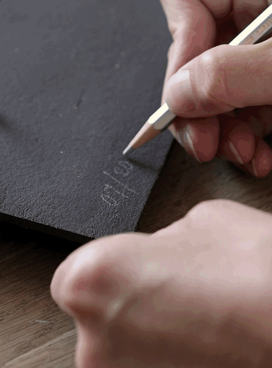 Studio JOA process shot — hand inscribing a mark into the wet dark clay surface, part of making the Writings 001 piece