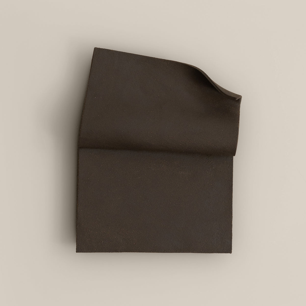Writings 001 by Studio JOA — Dark Brown folded stoneware wall piece, photographed against a plain wall