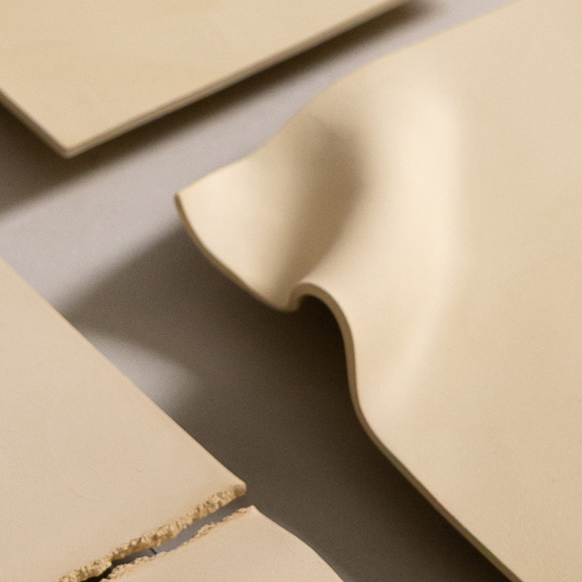 Studio JOA — Butter Yellow stoneware wall piece in the studio, resting on a table beside other Writings pieces