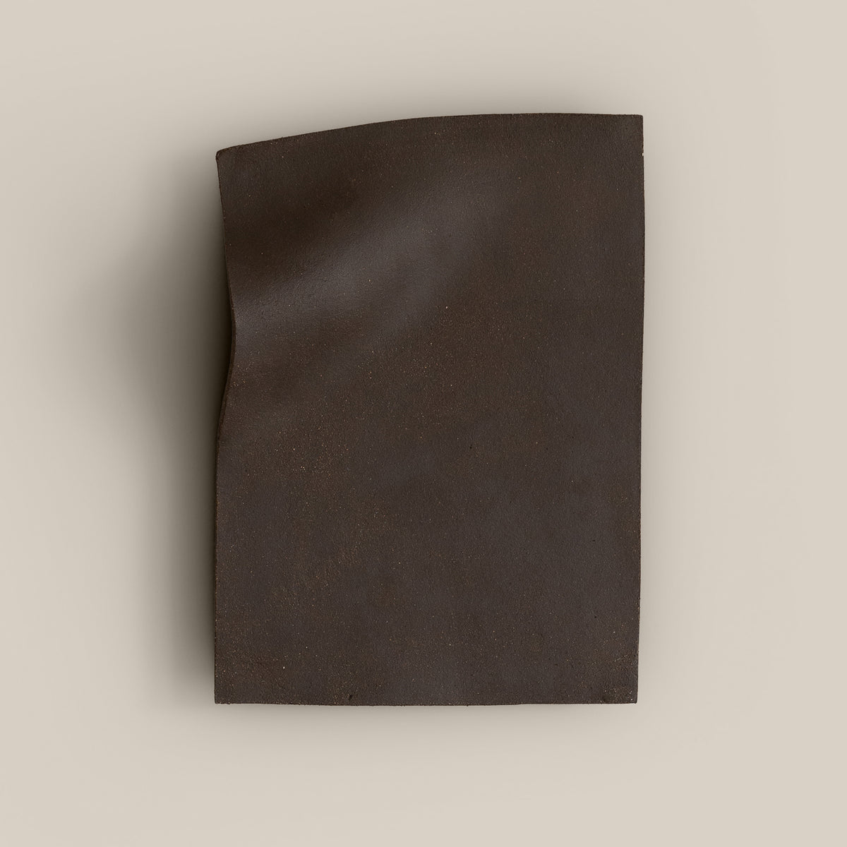 Writings 003 by Studio JOA — Dark Brown stoneware wall piece with a pinched vertical fold along one edge, photographed against a plain wall
