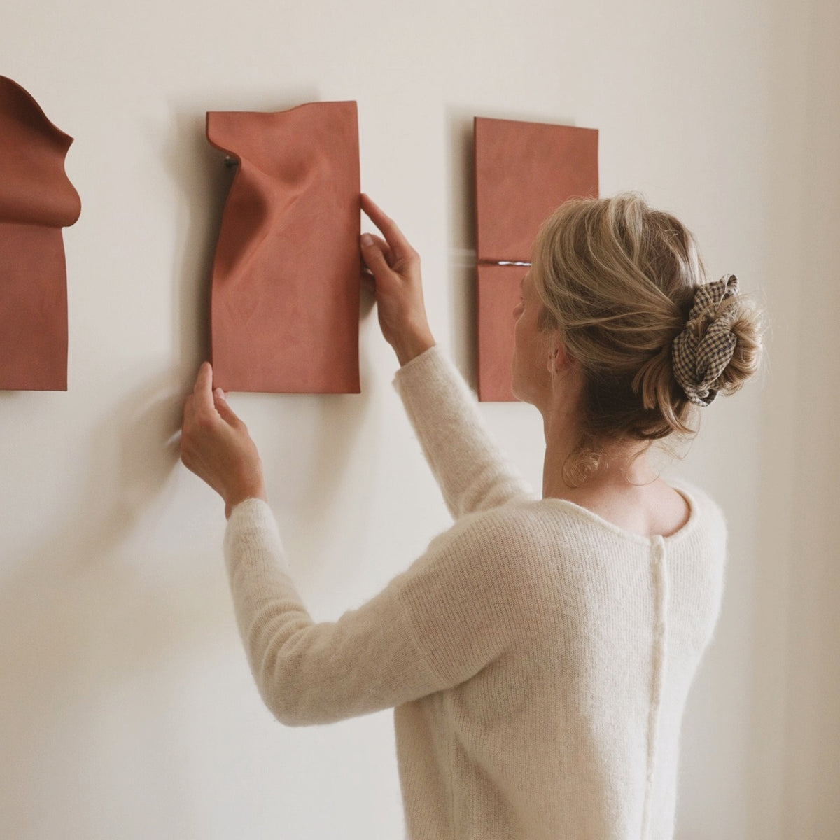 Studio JOA — Stone Red stoneware wall pieces being hung on the wall, shown together with two other Writings pieces