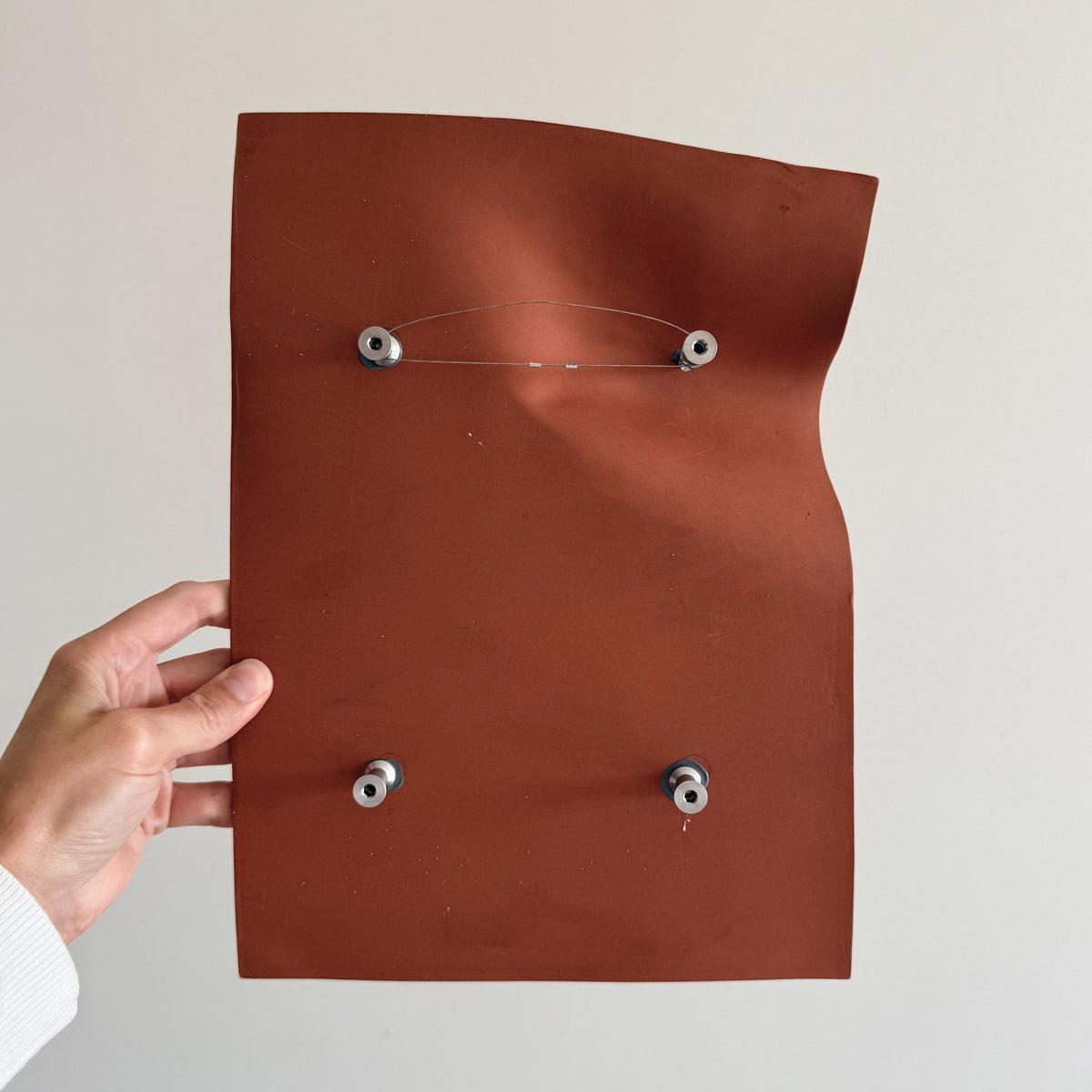 Writings 003 by Studio JOA — back of the Stone Red stoneware wall piece, showing the custom mounting hardware and hanging wire