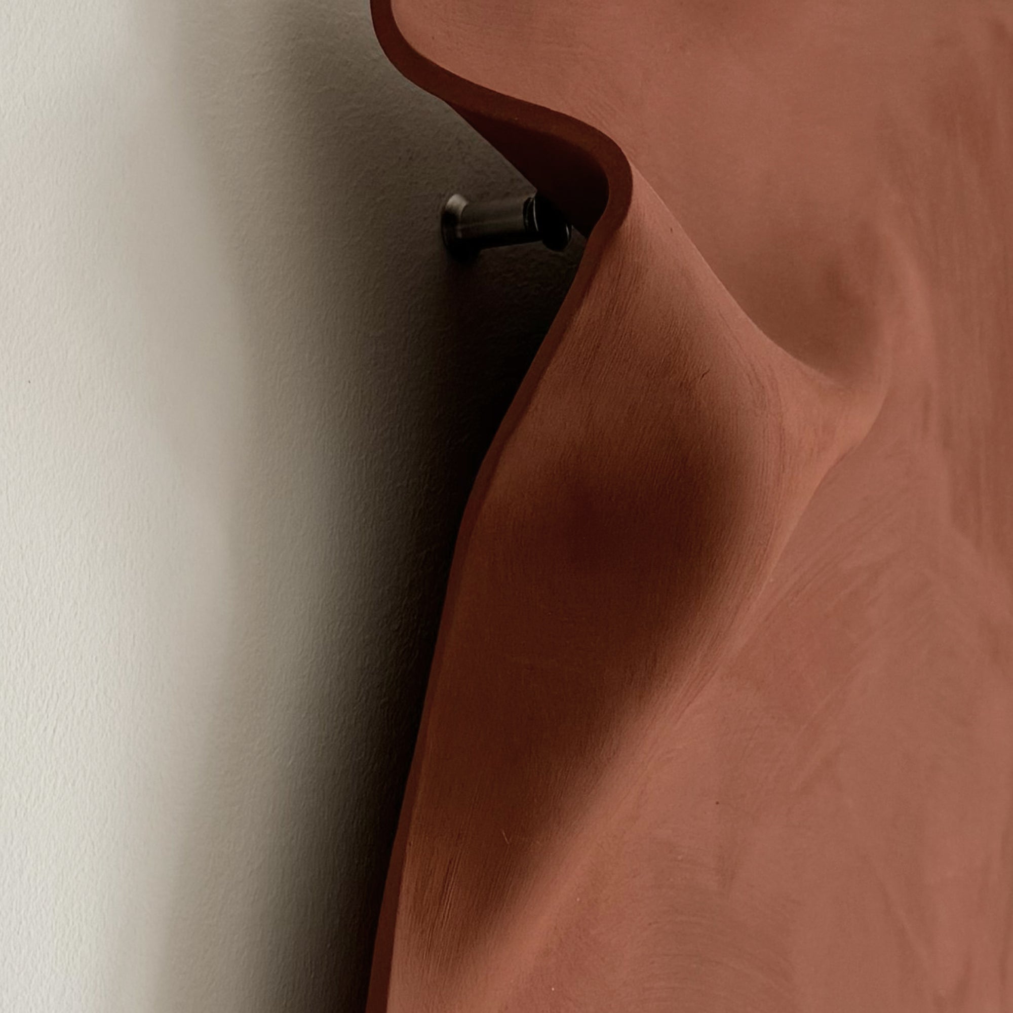 Writings 003 by Studio JOA — side view of the Stone Red stoneware wall piece, showing the mounting point that holds it off the wall