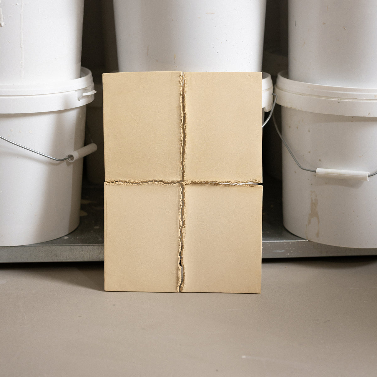 Studio JOA — Butter Yellow stoneware wall piece standing upright in the studio, leaning against storage buckets