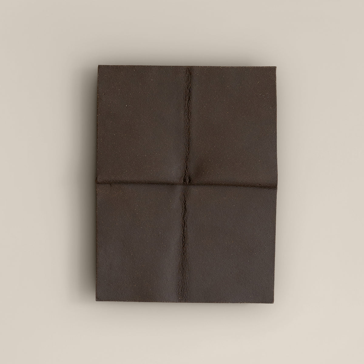 Writings 004 by Studio JOA — Dark Brown stoneware wall piece divided into four panels by a cross-shaped seam, photographed against a plain wall