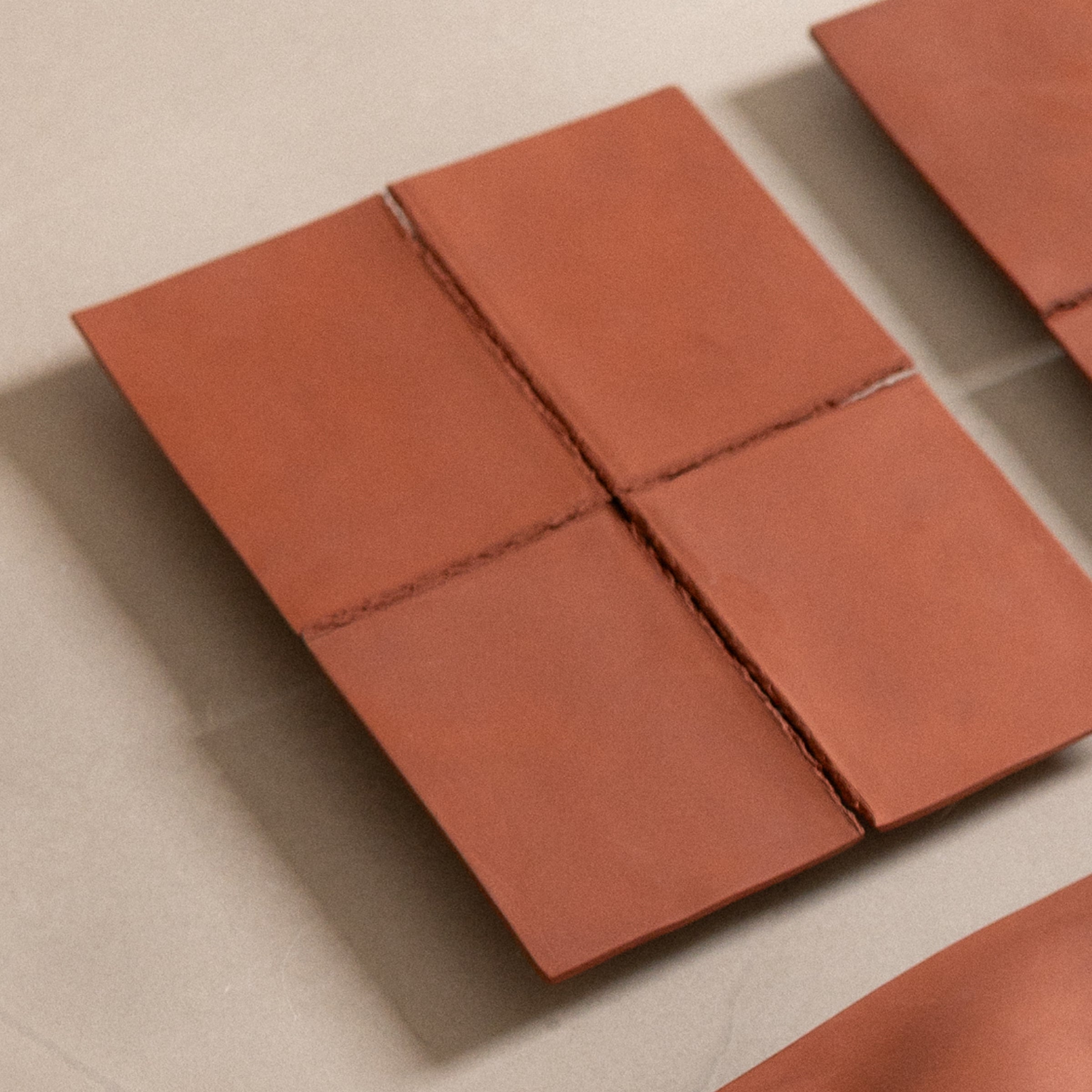 Studio JOA — Stone Red stoneware wall piece in the studio, resting on a counter beside another Writings piece